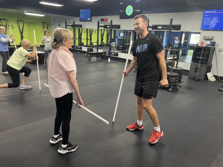 Jake Raecker explains a PVC pipe exercise to an Age On client.
