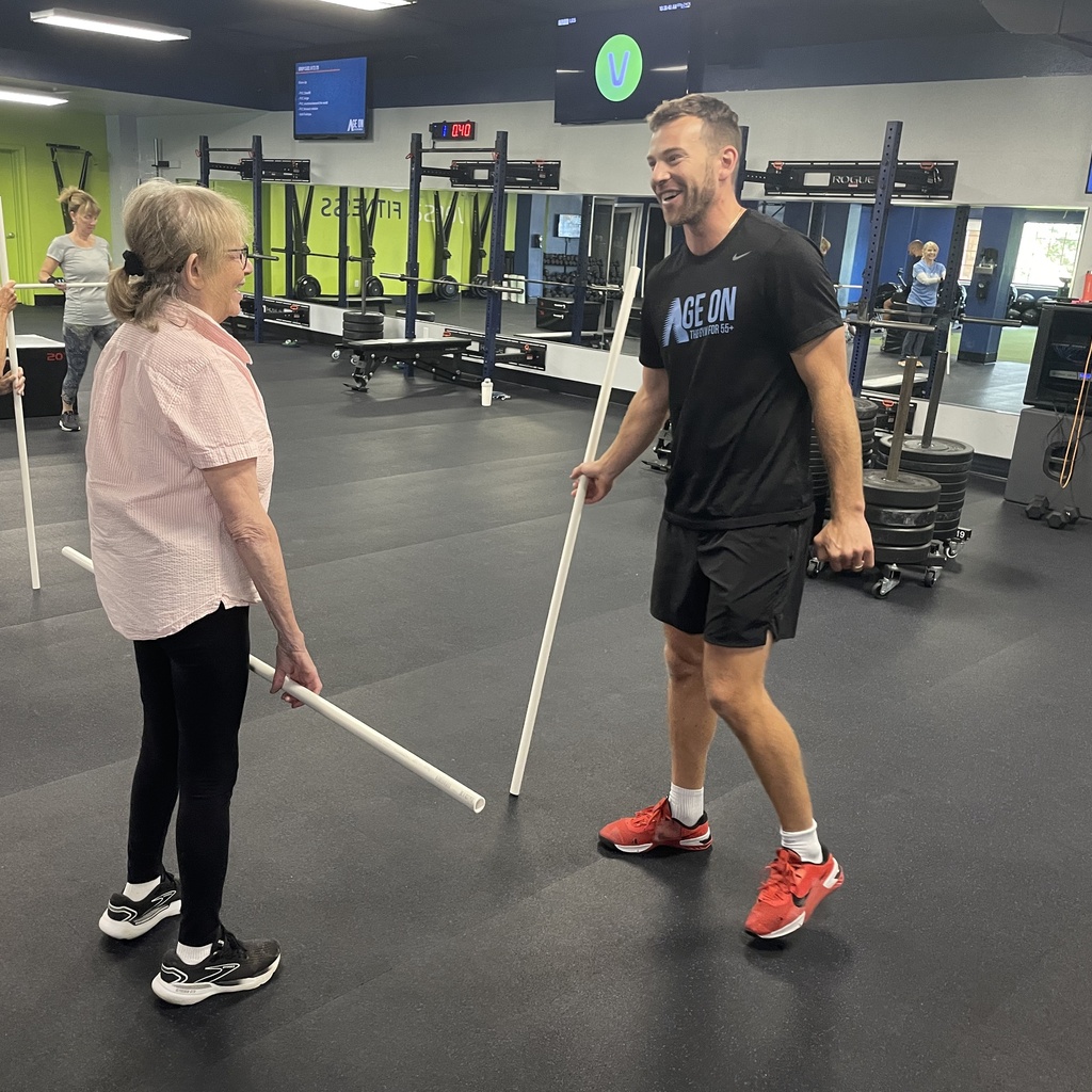 Jake Raecker explains PVC pipe exercise to a client at Age On Fitness