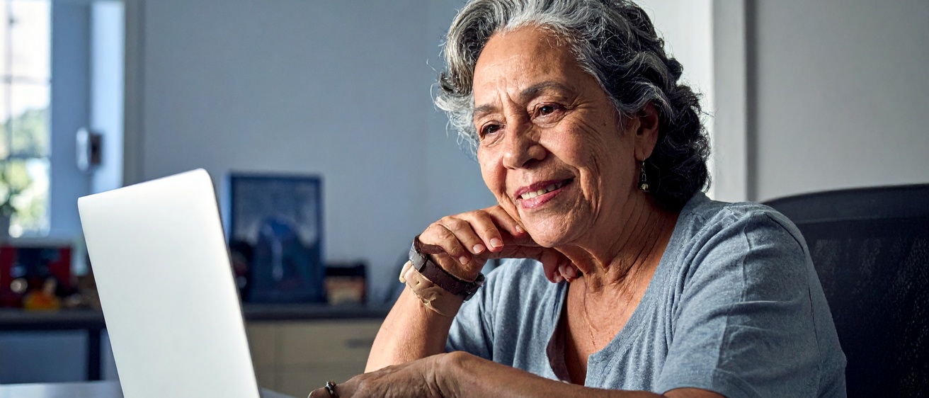 AI generated image of ethnically diverse woman in her 70s using computer