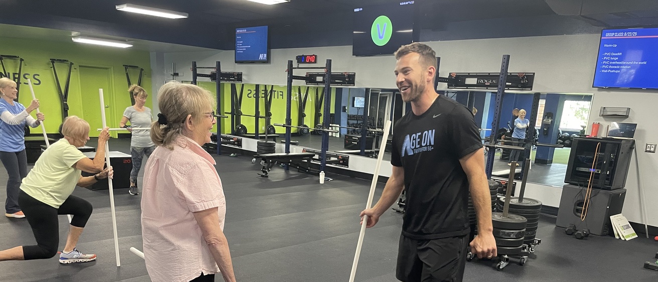 Jake Raecker explains PVC pipe exercise to a client at Age On Fitness